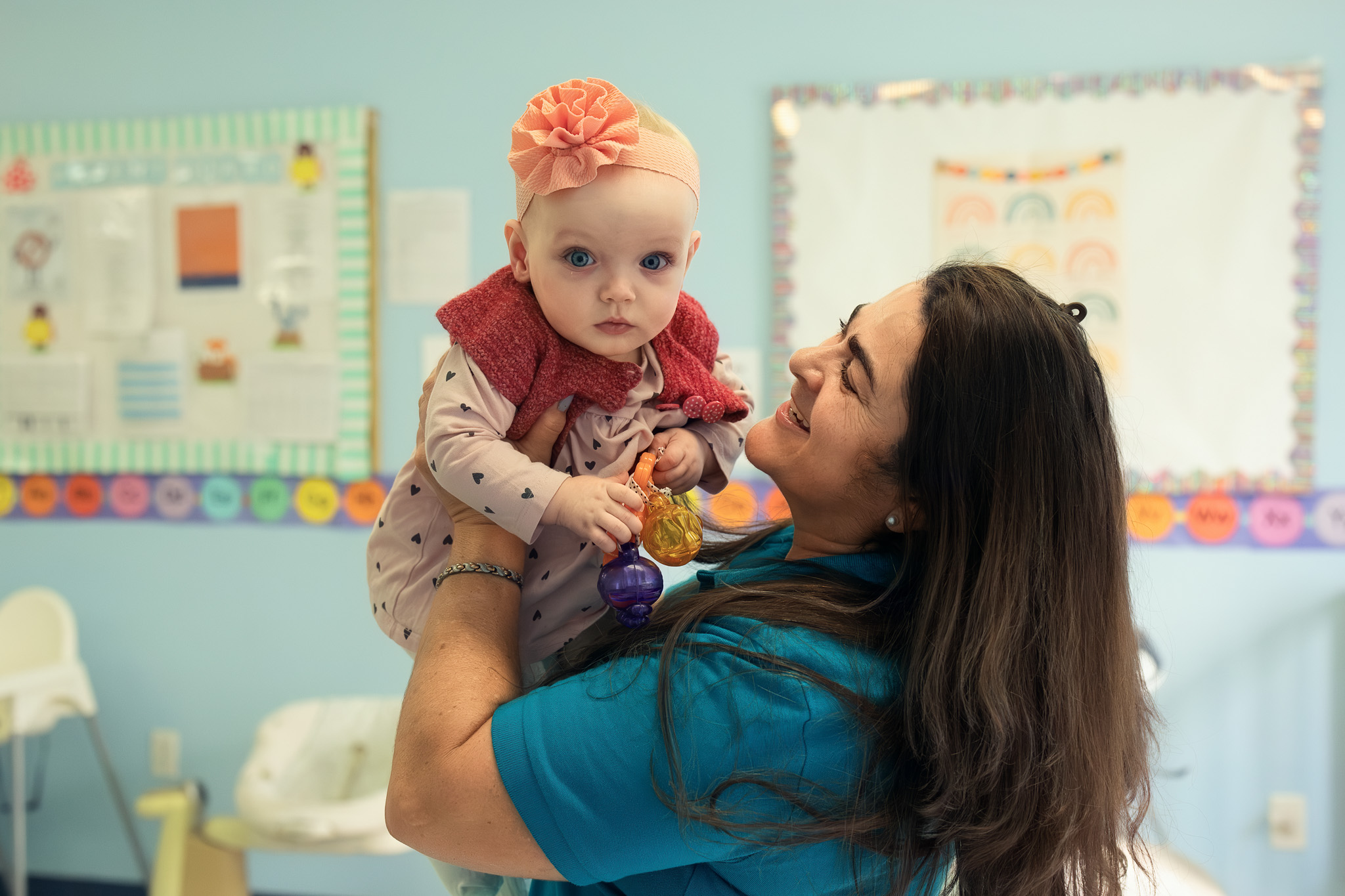 Teacher lifting a smiling baby — warm parent communication moment