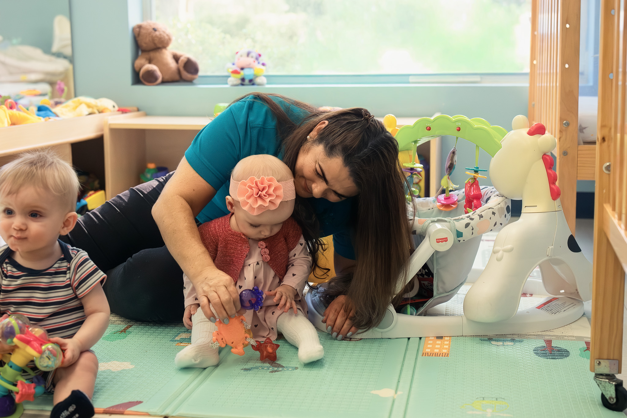 Teacher caring for an infant in a secure classroom at Little Newtons Academy