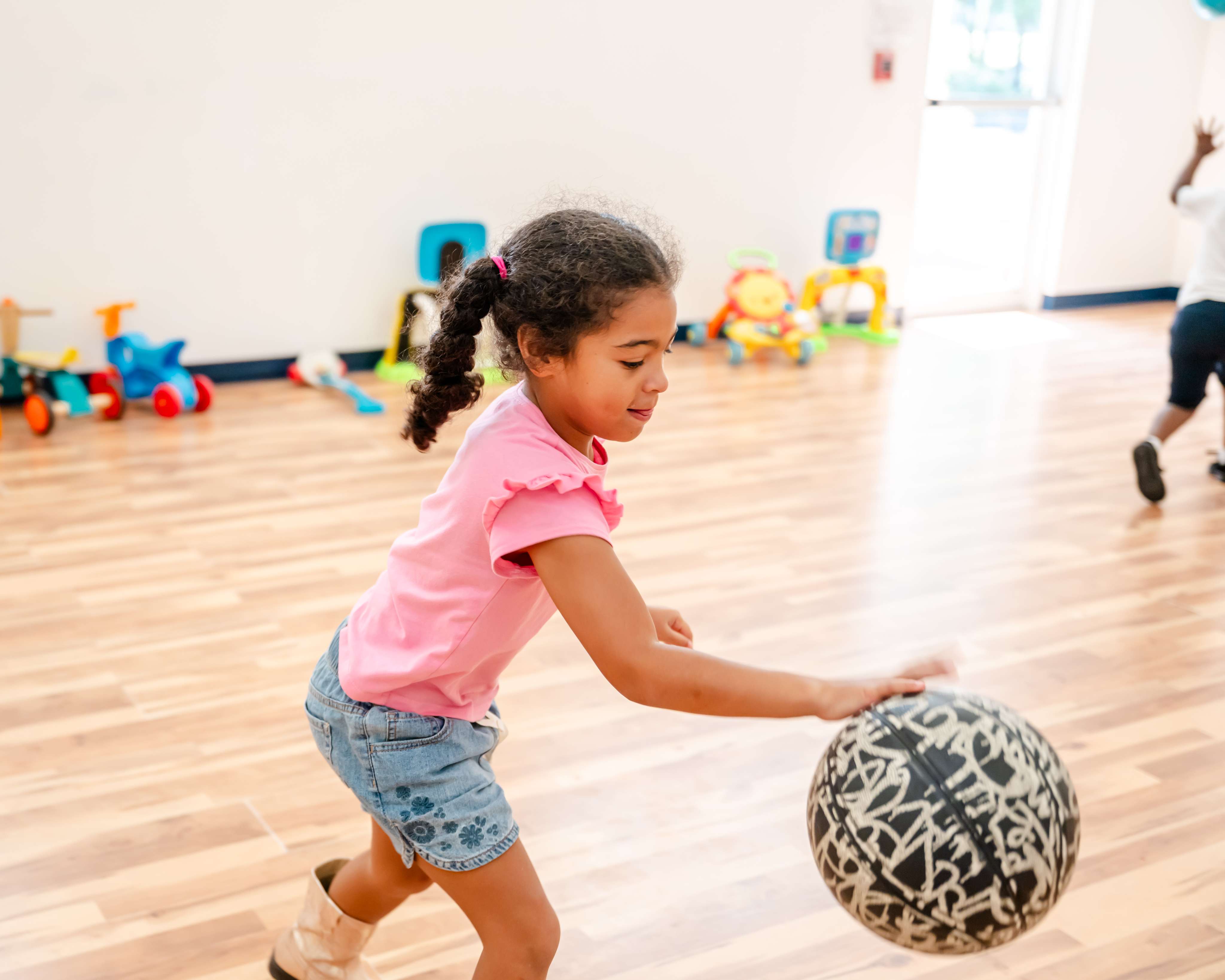 A child dribbling a basketball in the indoor gymnasium at Little Newtons Academy Heathrow