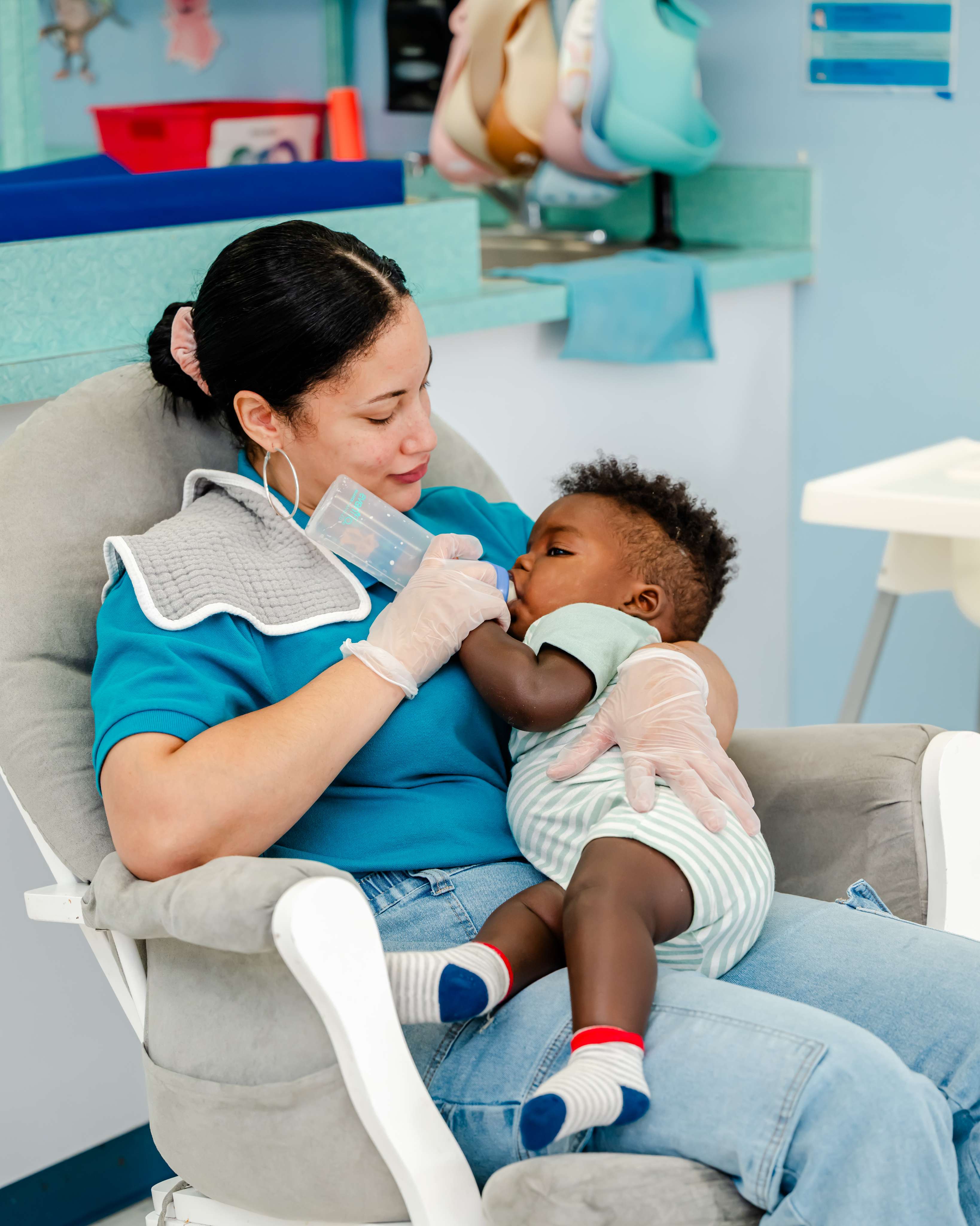 A teacher giving an infant a bottle during a calm, nurturing start to the day