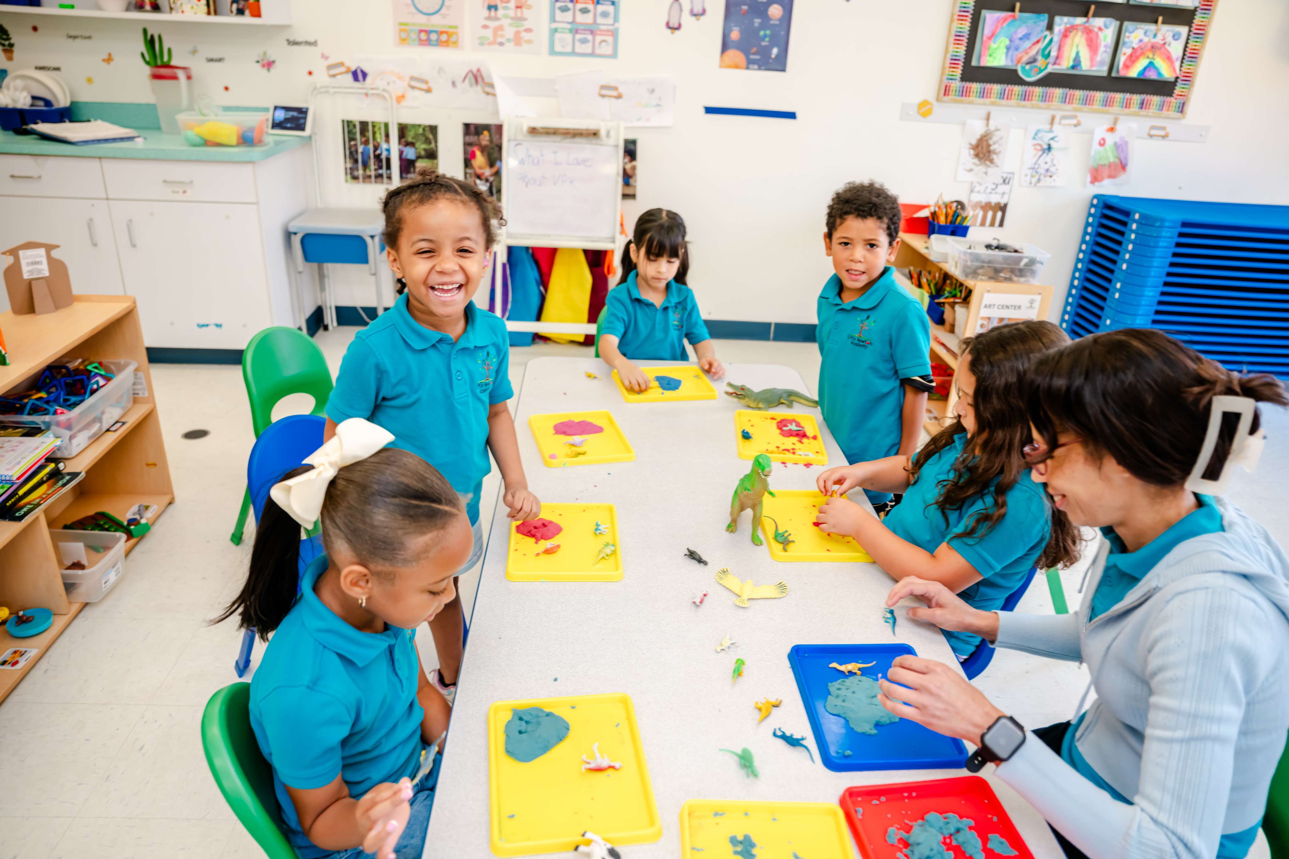 Children making colorful creations with playdough alongside their teacher
